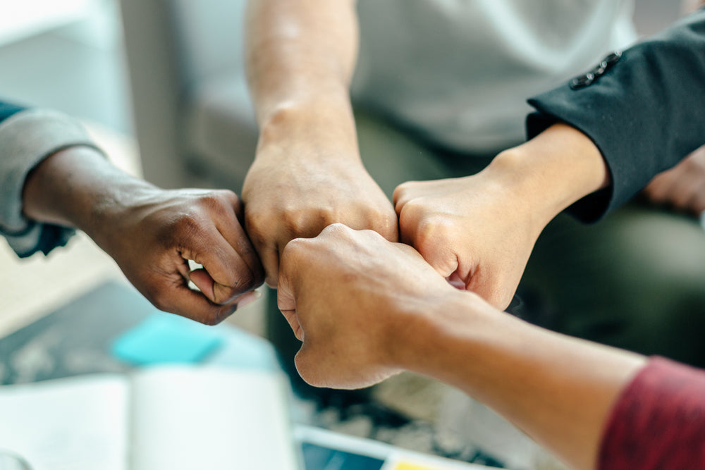 Four people fist bumping each other 