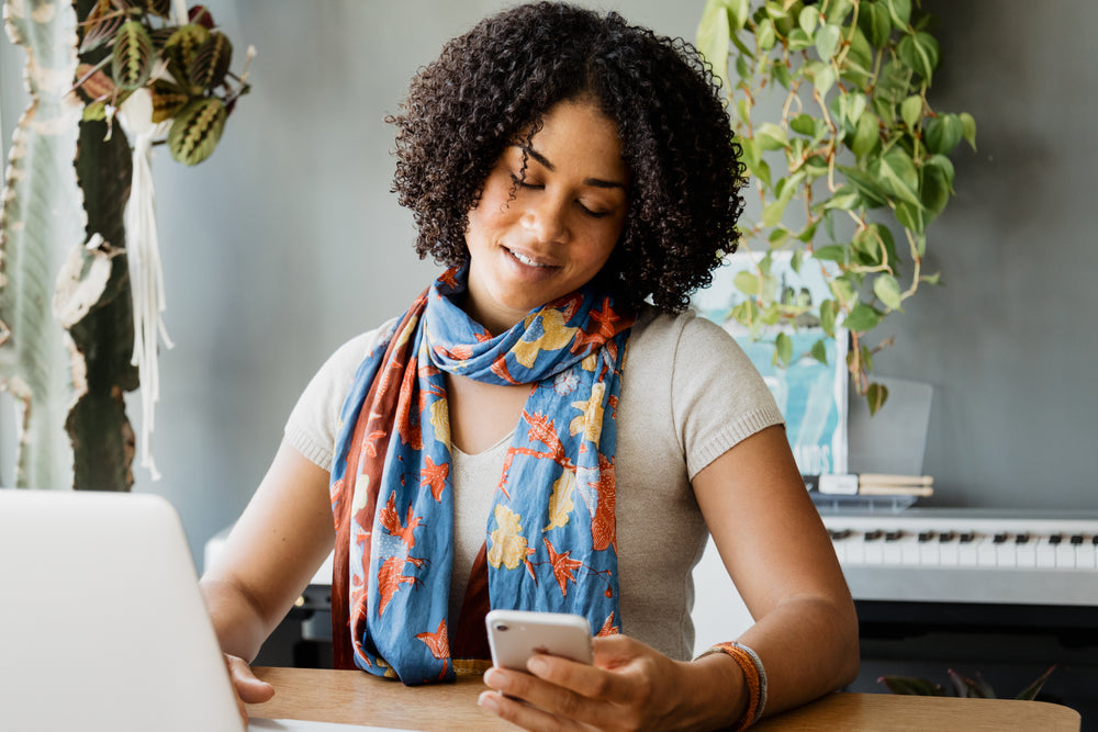 Woman on a laptop and looking at her cell phone